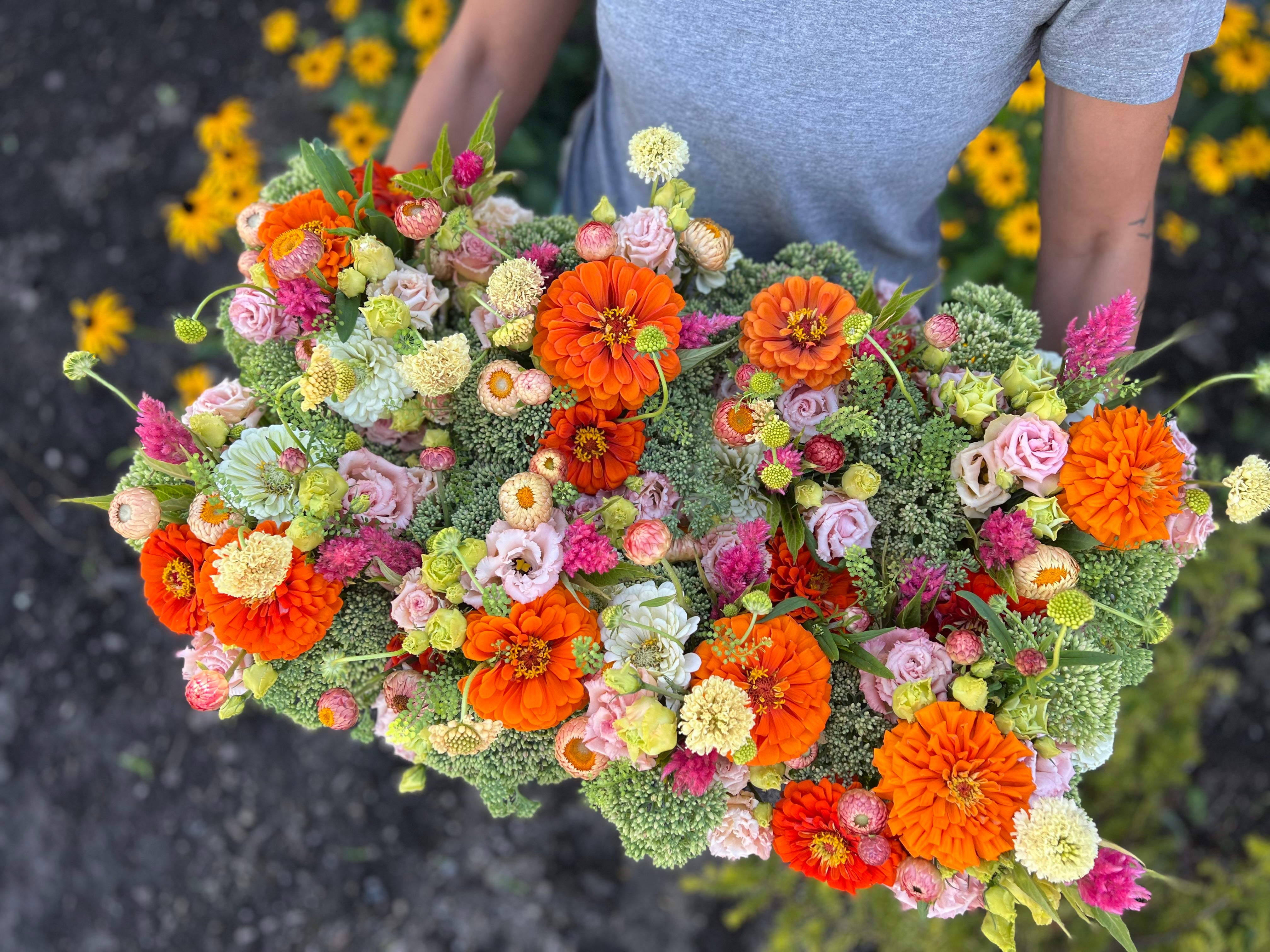 A display of eight mason jar arrangements in bright, summer colours.