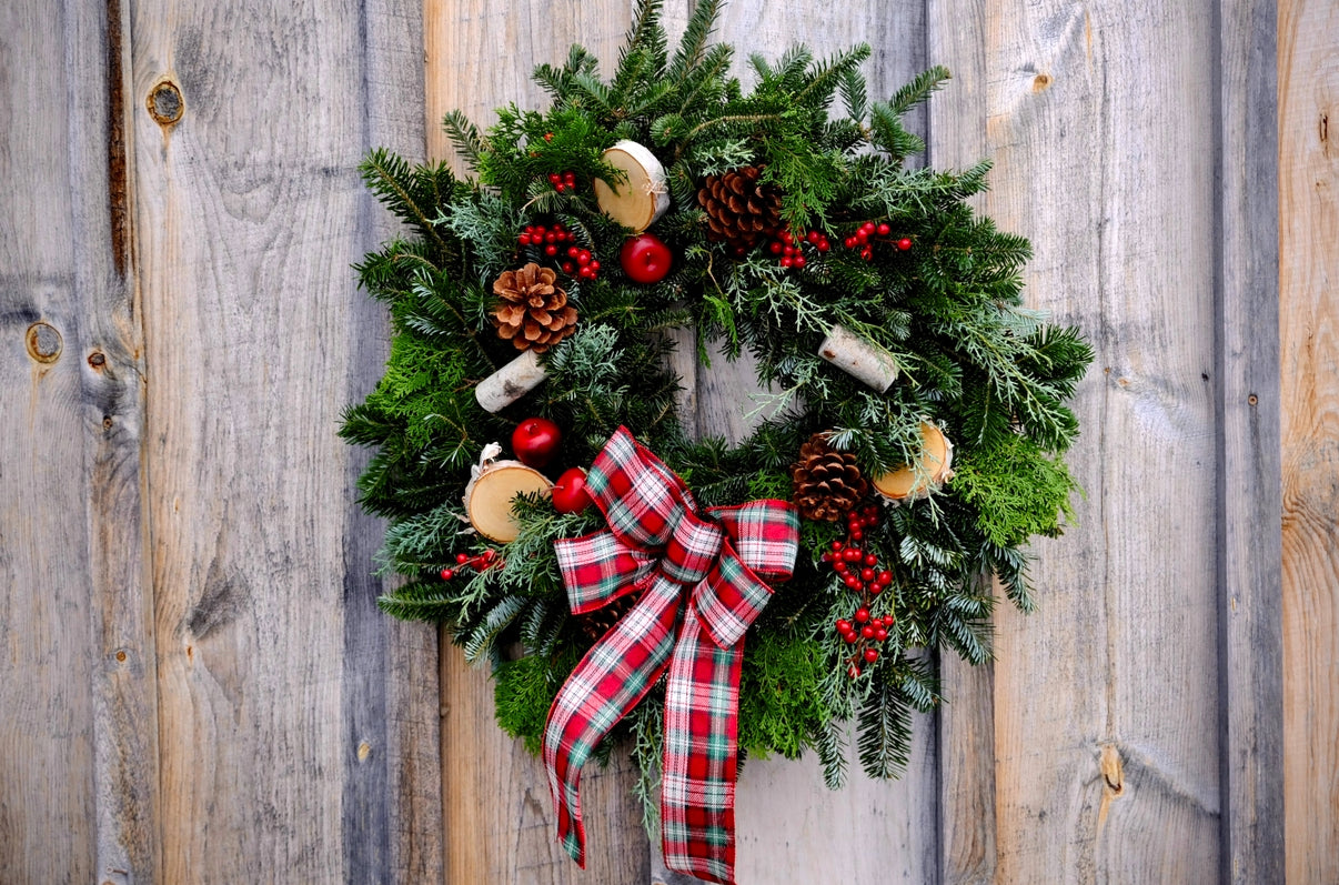 Christmas wreath with a plaid bow on a wooden door