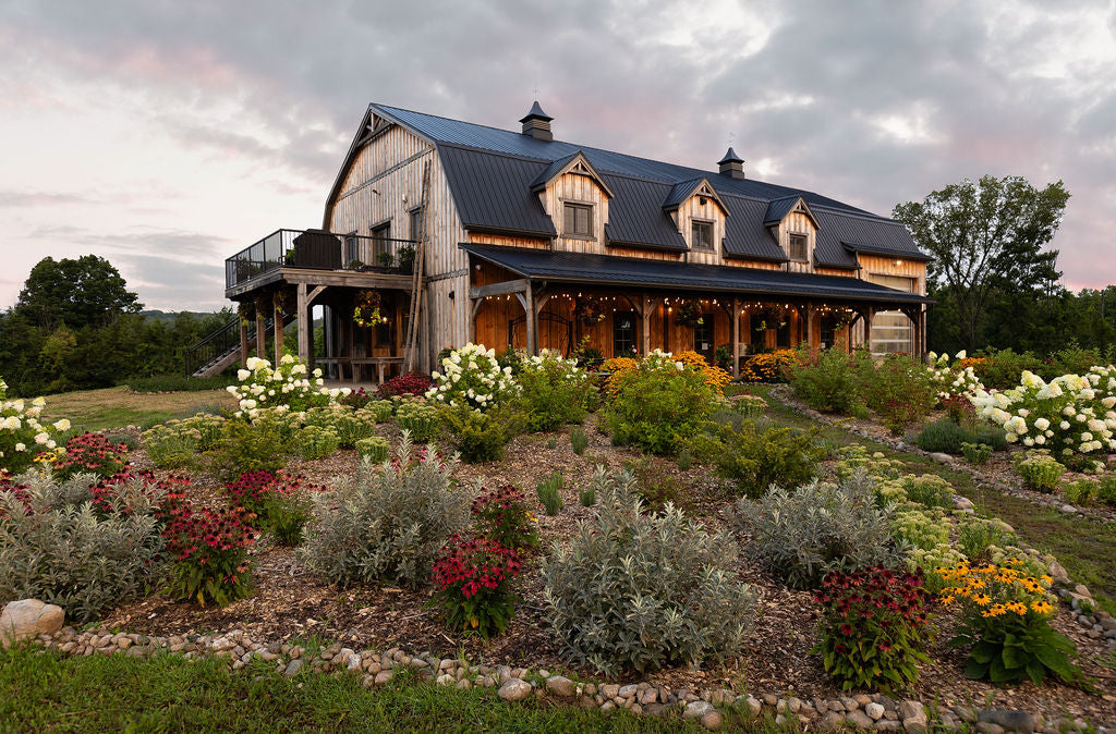 Side angle showing wooden barn behind a perennial garden.