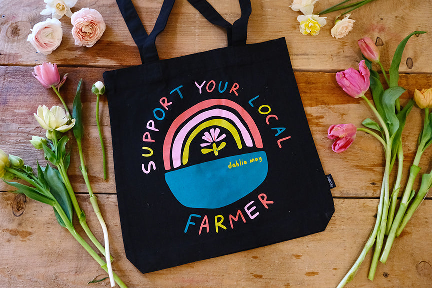 Black canvas bag with rainbow logo saying support your local farmer in pink, yellow, teal and coral.