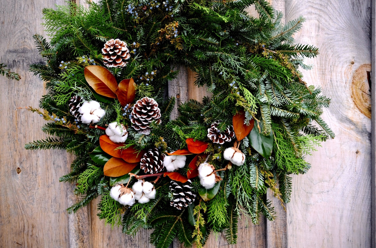 Christmas wreath with greenery, pinecones, and cotton on a wooden background