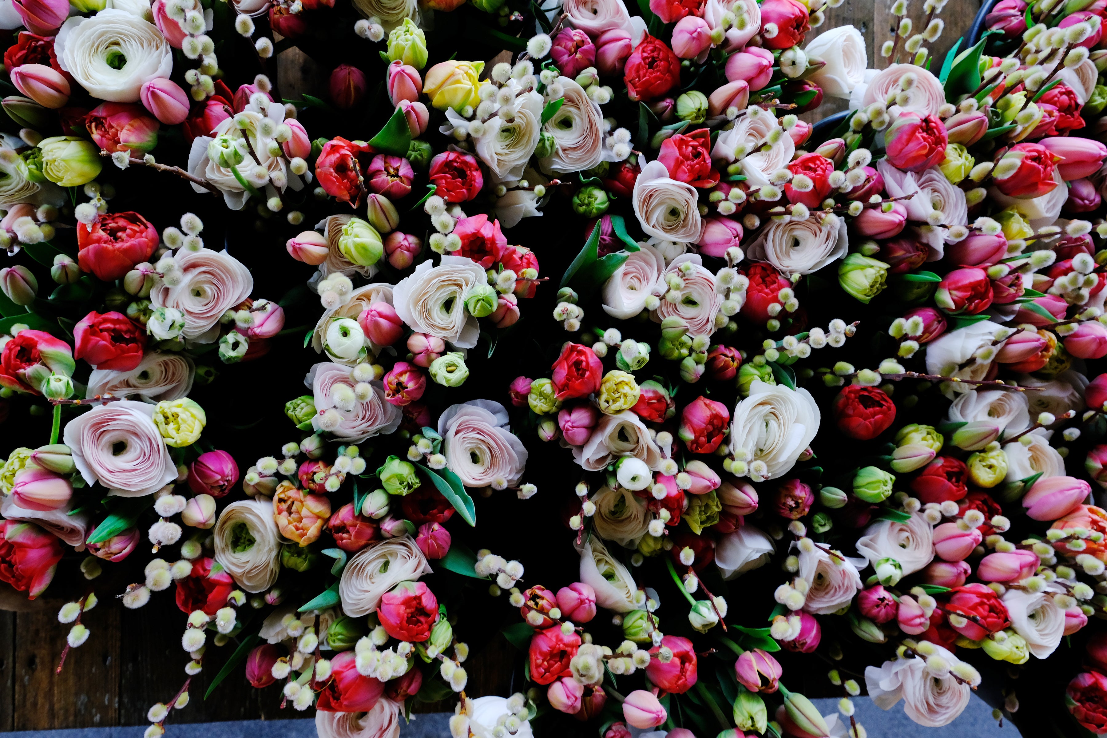 Close-up of bouquets featuring ranunculus, tulips and pussy willow stems.