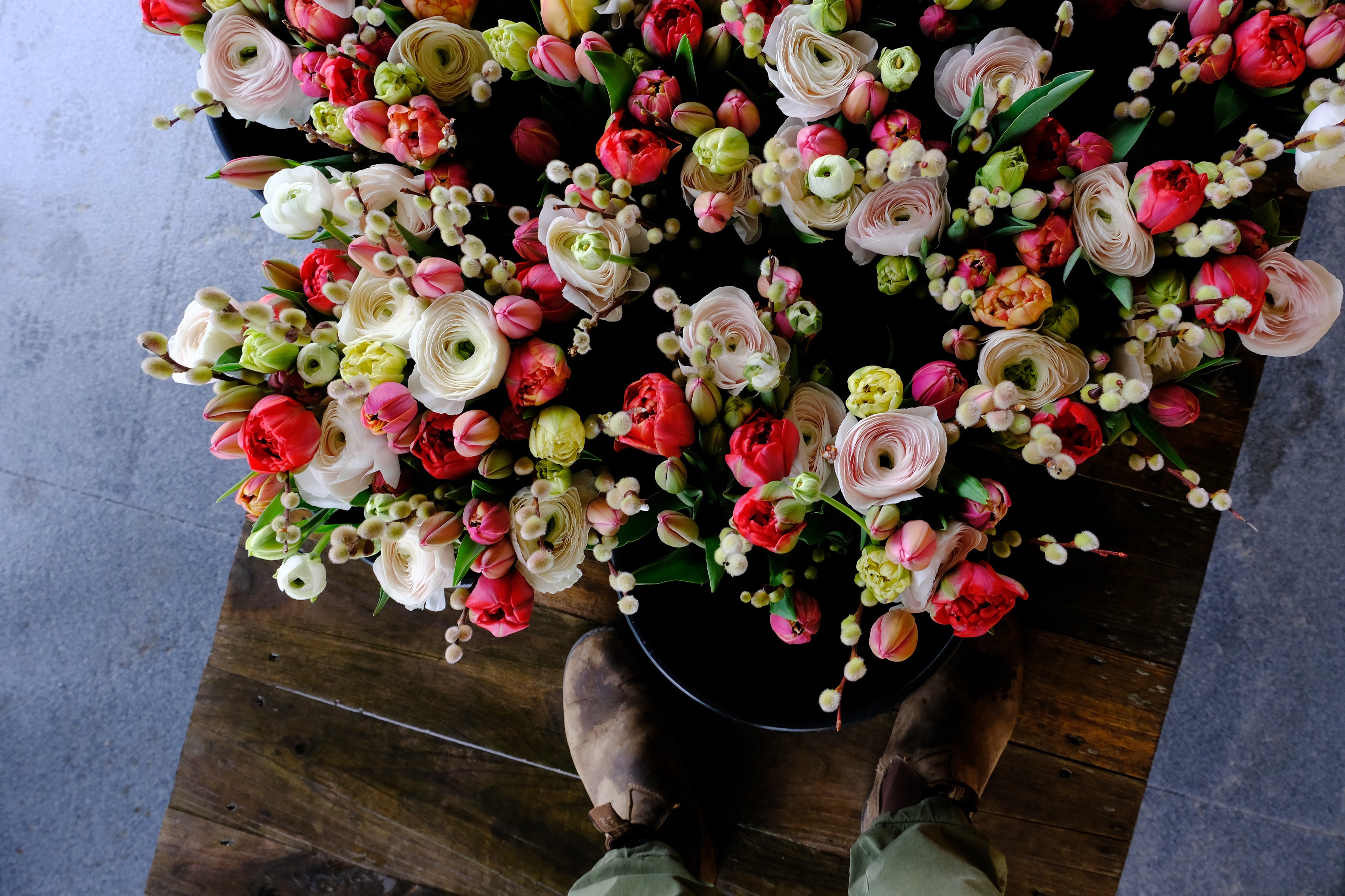 Overhead shot of bouquets in buckets featuring ranunuculs, tulips and pussy willow.