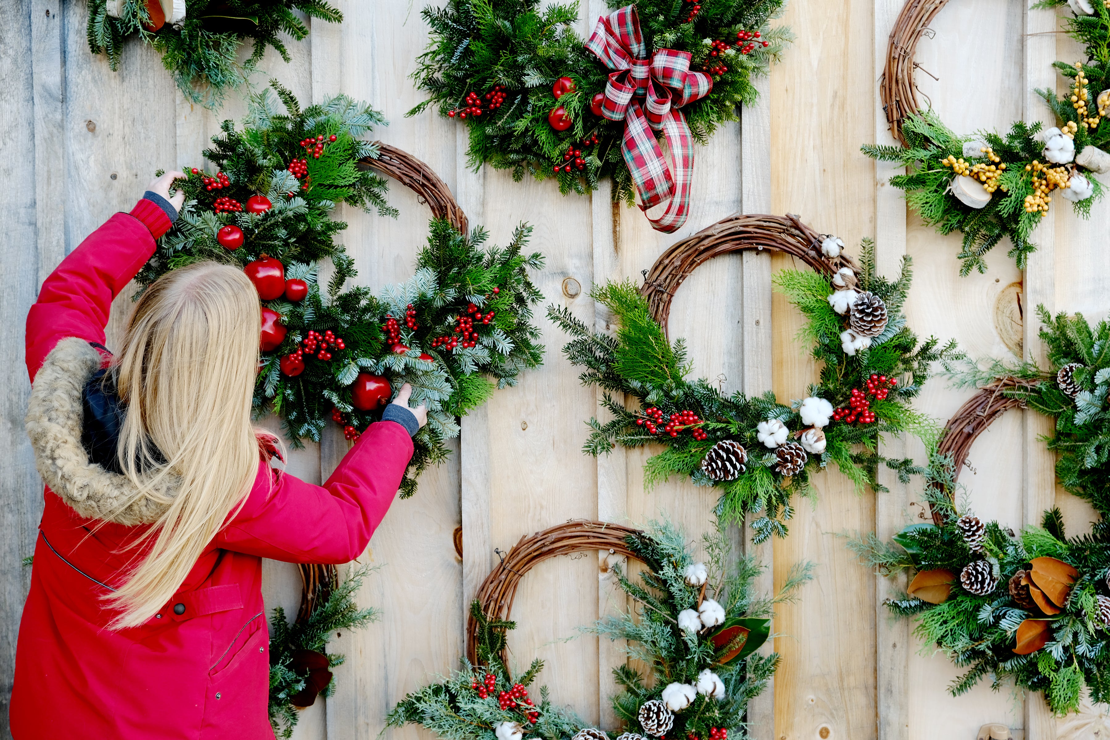Hanging up an asymmetrical grapevine wreath on a wooden wall of other wreaths. 