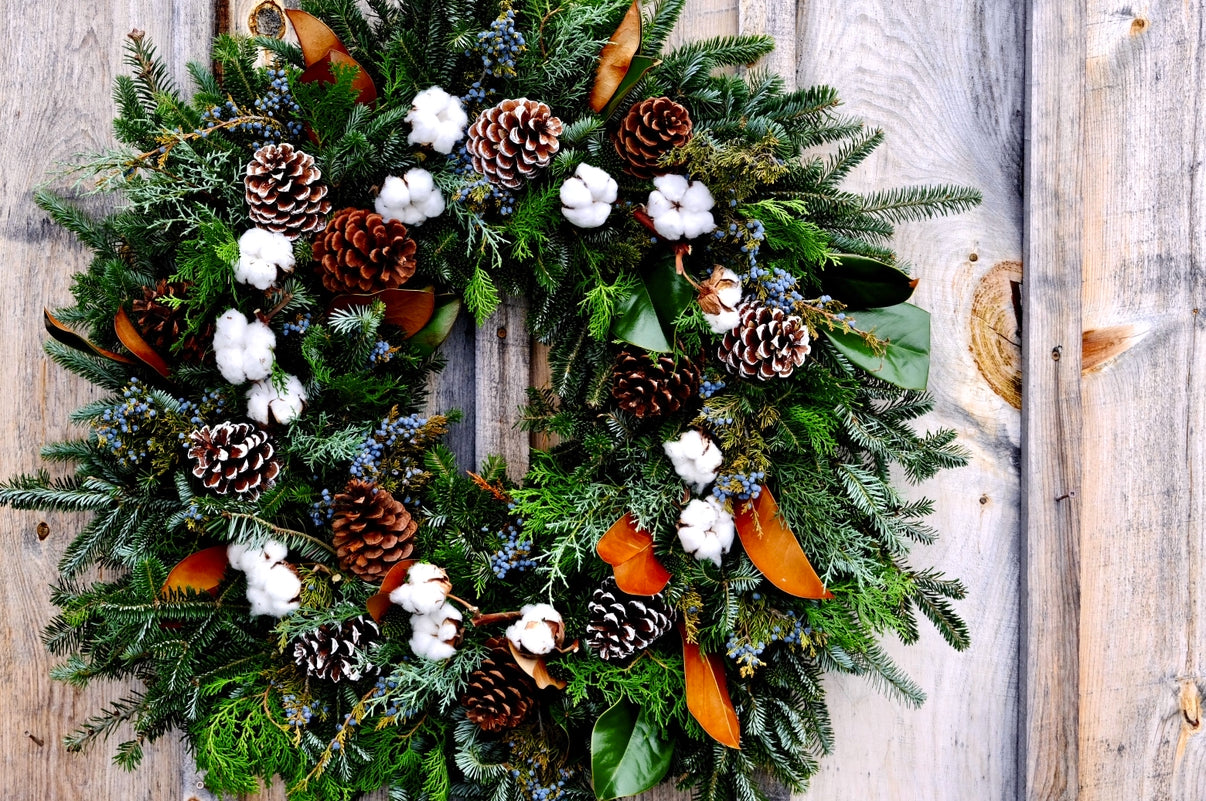 Christmas wreath with pine cones, cotton balls, and magnolia leaves on a wooden background